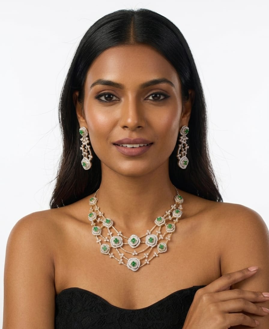 A woman modeling a matching jewelry set featuring a multi-strand necklace and matching drop earrings with green stones and silver-toned settings, against a plain light gray background.