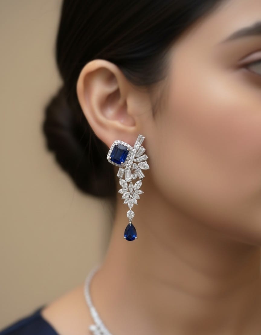 Close-up of a woman wearing a sparkling earring with a blue gemstone.