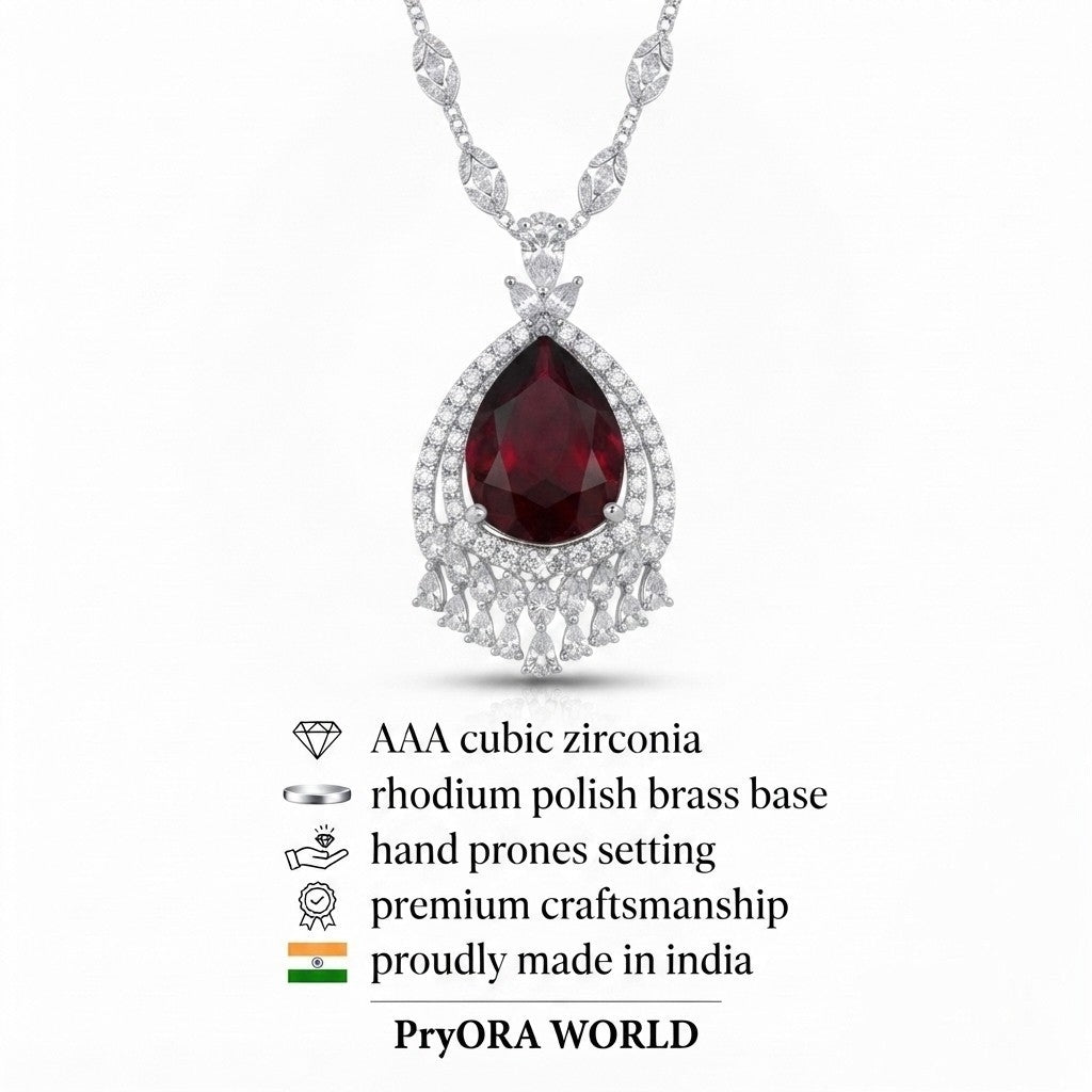 A silver-tone pendant necklace featuring a teardrop-shaped deep red gemstone surrounded by clear stones, shown on a white background with product feature icons and the text 'PryORA WORLD' below.