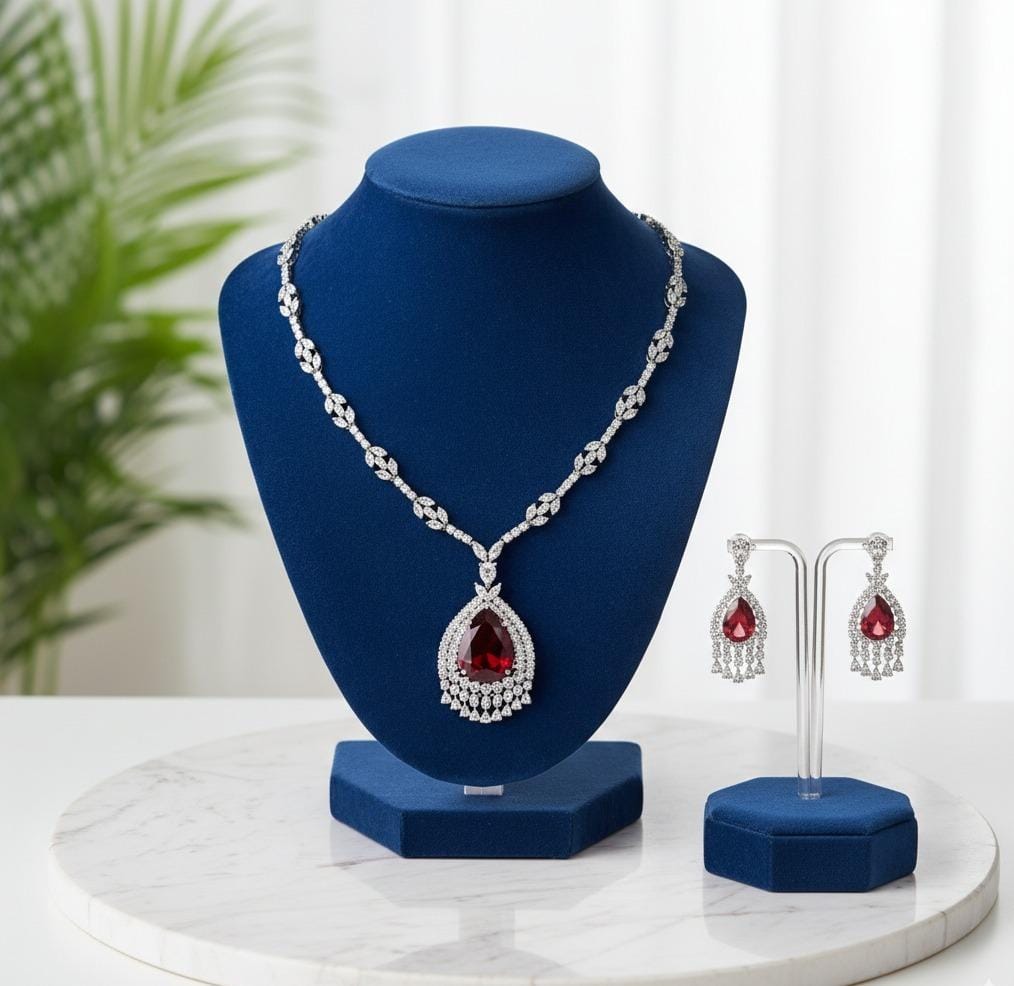 Jewelry set with necklace and earrings on a blue stand against a white background