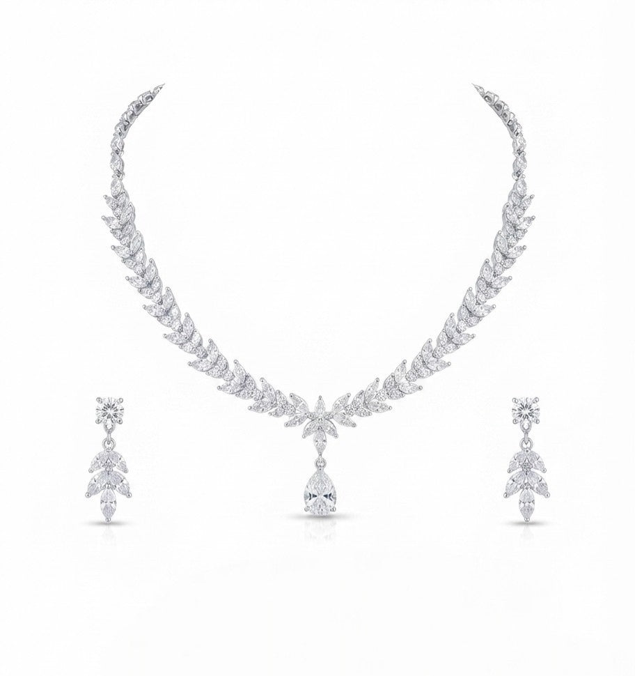 A white gold or platinum jewelry set featuring a leaf-patterned necklace with a teardrop pendant and matching drop earrings, displayed on a clean white background.