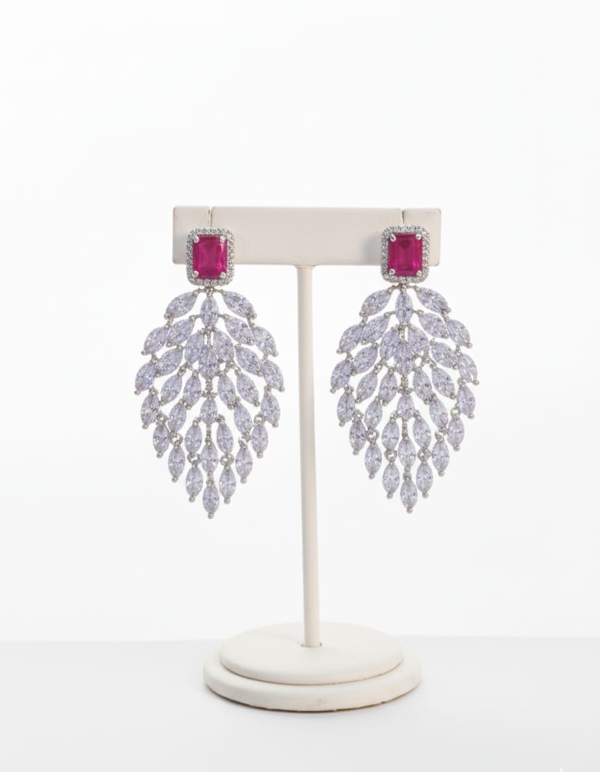 Pair of earrings with pink gemstones on a white stand against a white background
