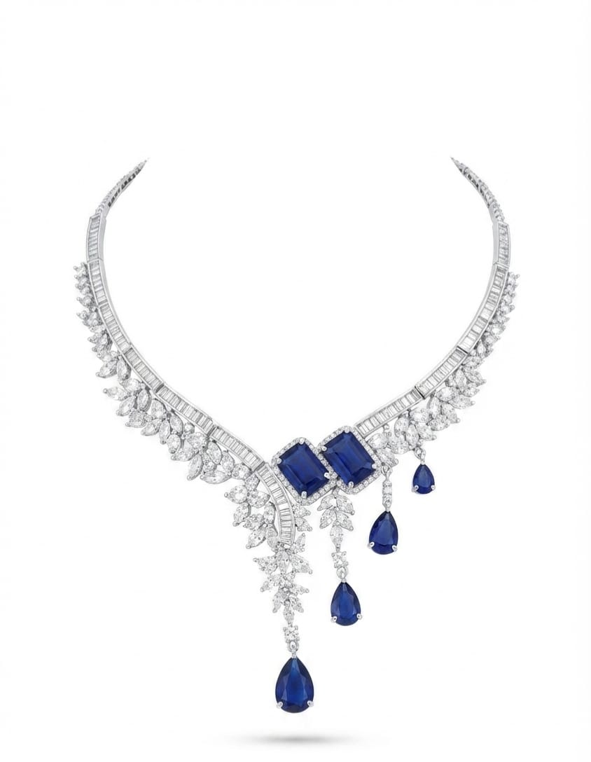 A luxury diamond and sapphire necklace featuring a curved silver-toned setting adorned with pavé diamonds, three rectangular blue sapphires at the center, and three cascading teardrop-shaped blue sapphires, shown on a plain white background.