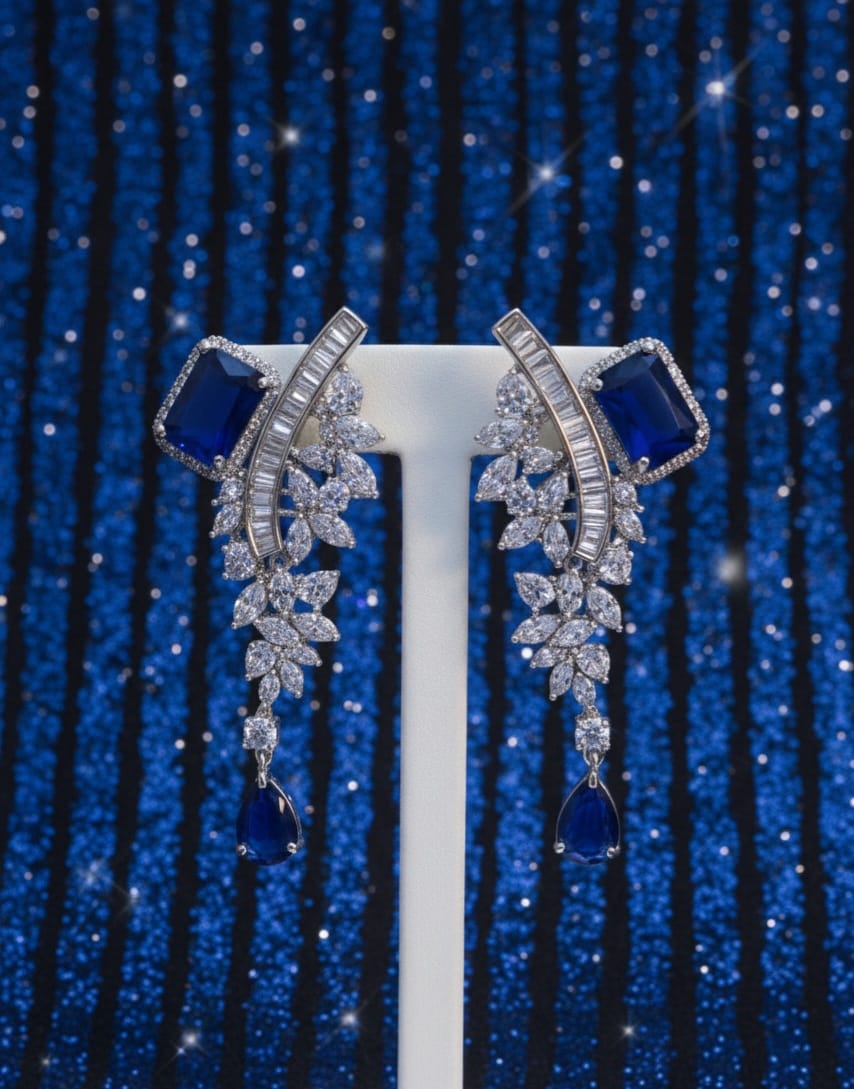 Pair of silver earrings with blue gemstones on a blue textured background